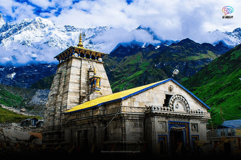 The sacred Kedarnath Temple, a historic stone structure, stands tall against a dramatic backdrop of snow-capped mountains and cloudy skies in Uttarakhand.