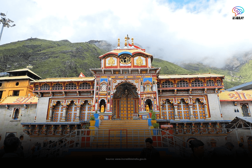 The vibrant and colorful facade of the Badrinath Temple, set against lush green mountains shrouded in mist in Uttarakhand.