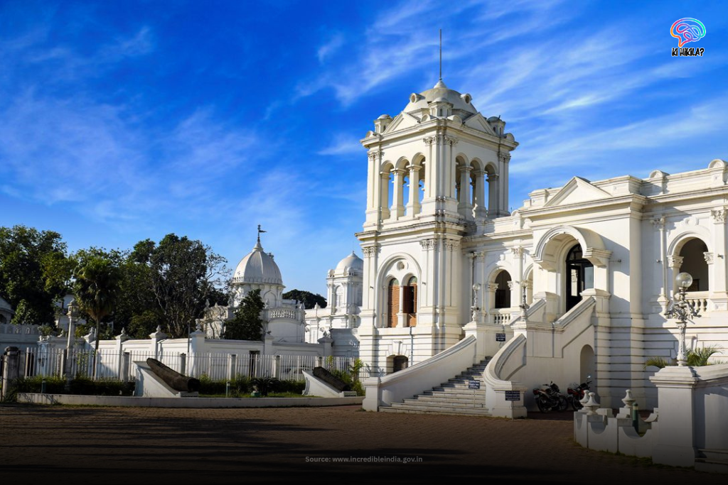 The grand, white Ujjayanta Palace in Agartala, Tripura, under a bright blue sky with wispy clouds, showcasing its Indo-Saracenic architecture.