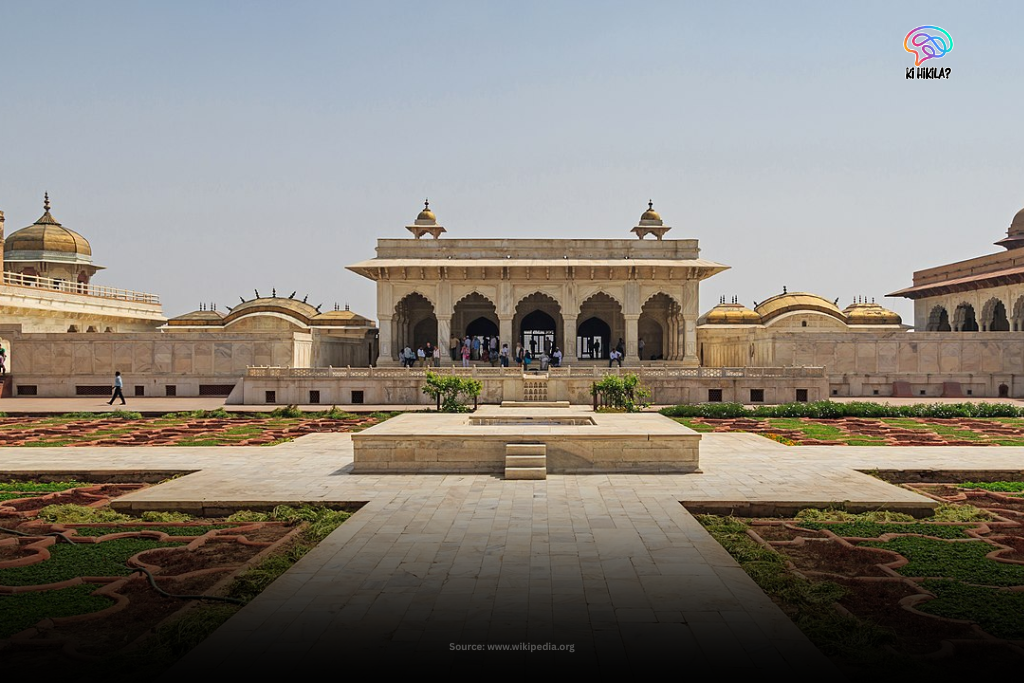 A view of the white marble pavilion inside Agra Fort with visitors walking around the garden courtyard.