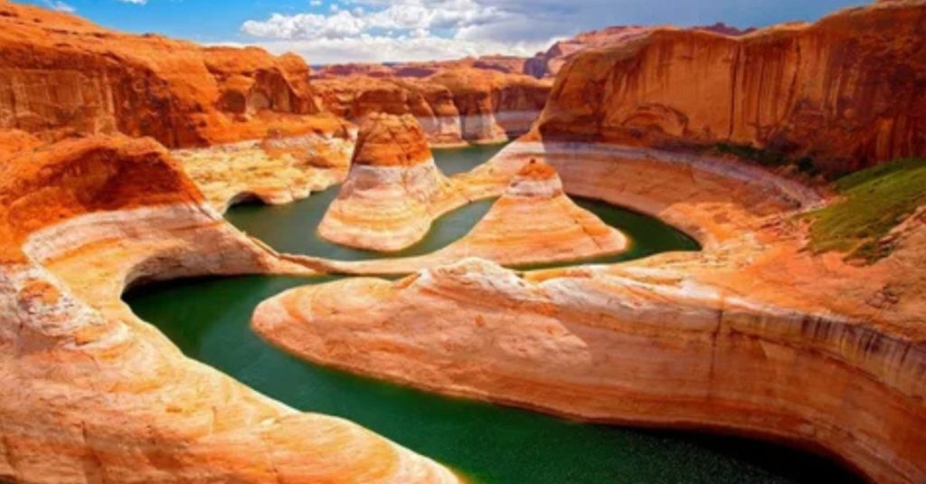 Wonderful Natural Wonder: How Grand Canyons Are Formed 1 A breathtaking view of a winding canyon with layered red rock formations and a greenish river curving through it, showcasing erosion and sedimentary layering.