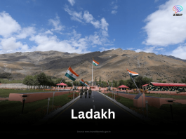 The Kargil War Memorial in Dras, Ladakh, with Indian flags lining the central walkway leading towards the rugged mountain backdrop.