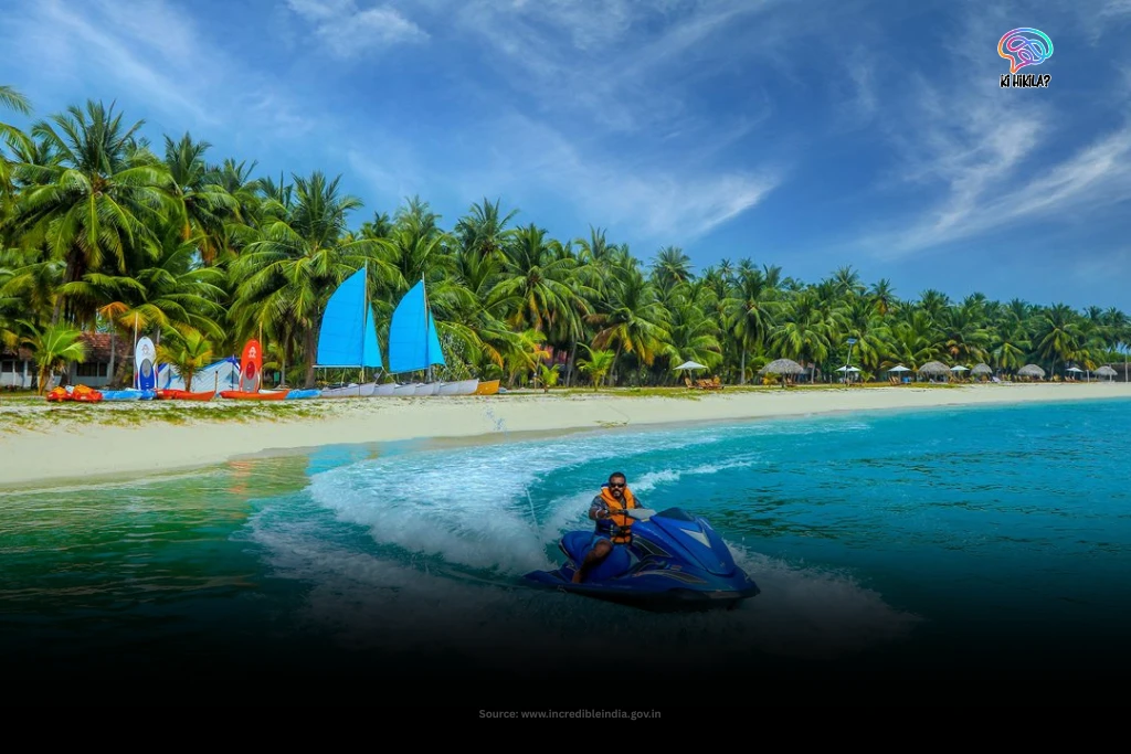 A person riding a jet ski in the turquoise waters off a white sand beach lined with palm trees in Lakshadweep.