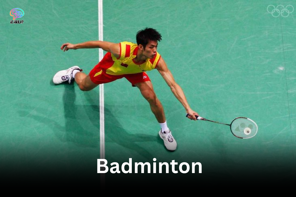 A male badminton player in a yellow and red jersey lunging low on a green court, representing Badminton in Olympic.